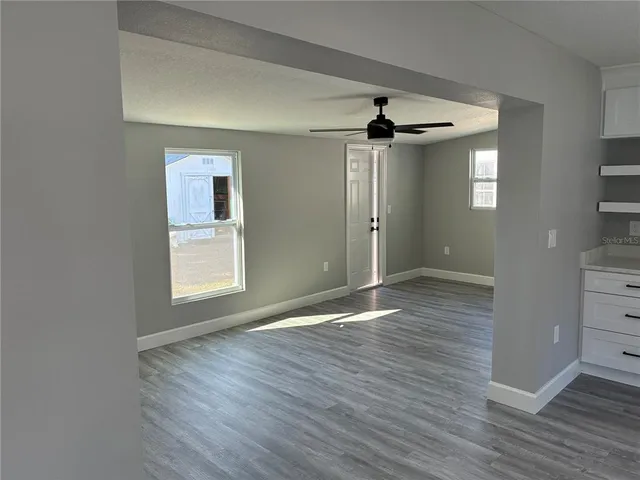 a view of an empty room with a window and wooden floor