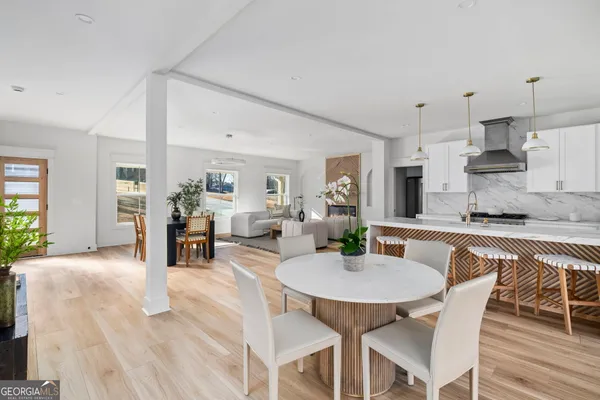a kitchen with stainless steel appliances kitchen island granite countertop a dining table chairs and white cabinets