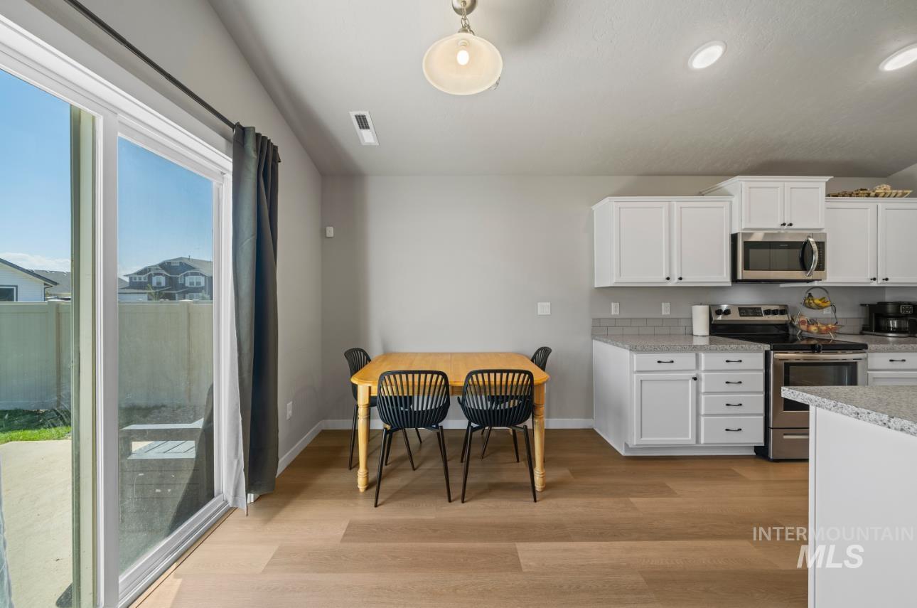 12443 Varga Street Caldwell, ID 83607 - Photo 11 of 27 Kitchen featuring appliances with stainless steel finishes, white cabinetry, light wood finished floors, recessed lighting, and hanging light fixtures