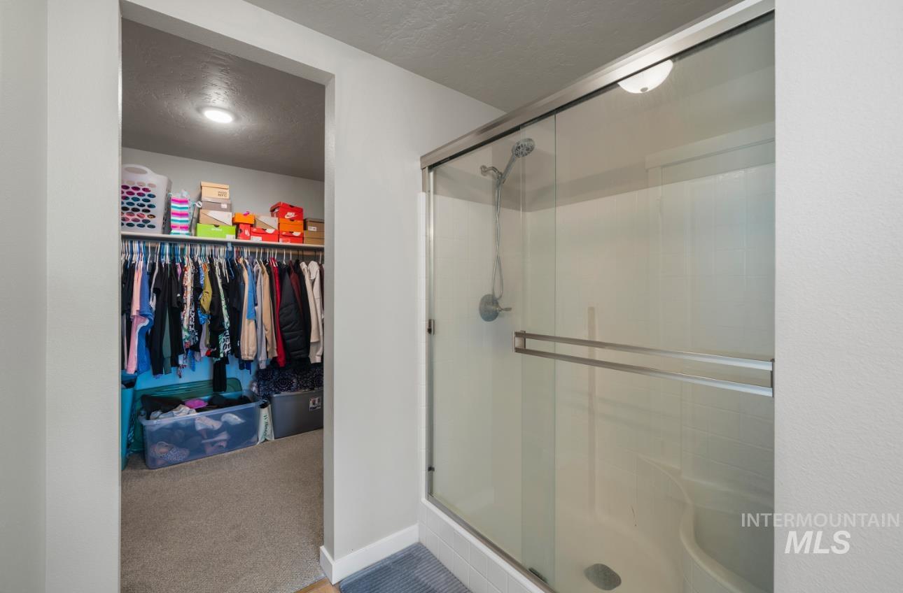 12443 Varga Street Caldwell, ID 83607 - Photo 18 of 27 Bathroom with a textured ceiling, a stall shower, and a walk in closet