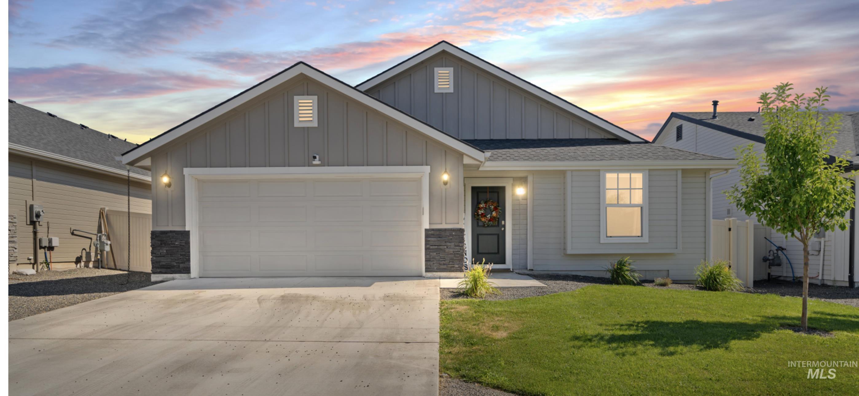 12443 Varga Street Caldwell, ID 83607 - Photo 2 of 27 View of front of property with board and batten siding, an attached garage, stone siding, concrete driveway, and a lawn