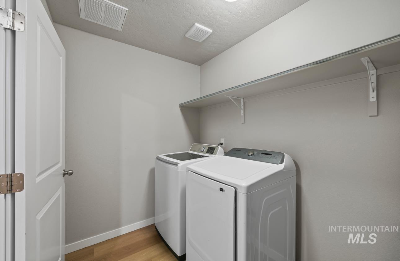 12443 Varga Street Caldwell, ID 83607 - Photo 23 of 27 Laundry room with washer and dryer, a textured ceiling, and light wood-style floors