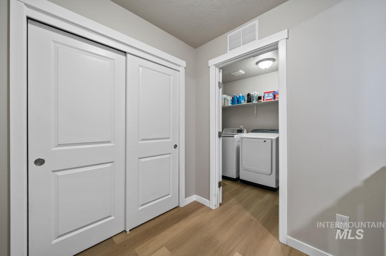 12443 Varga Street Caldwell, ID 83607 - Photo 26 of 27 Laundry room with separate washer and dryer, light wood finished floors, and a textured ceiling
