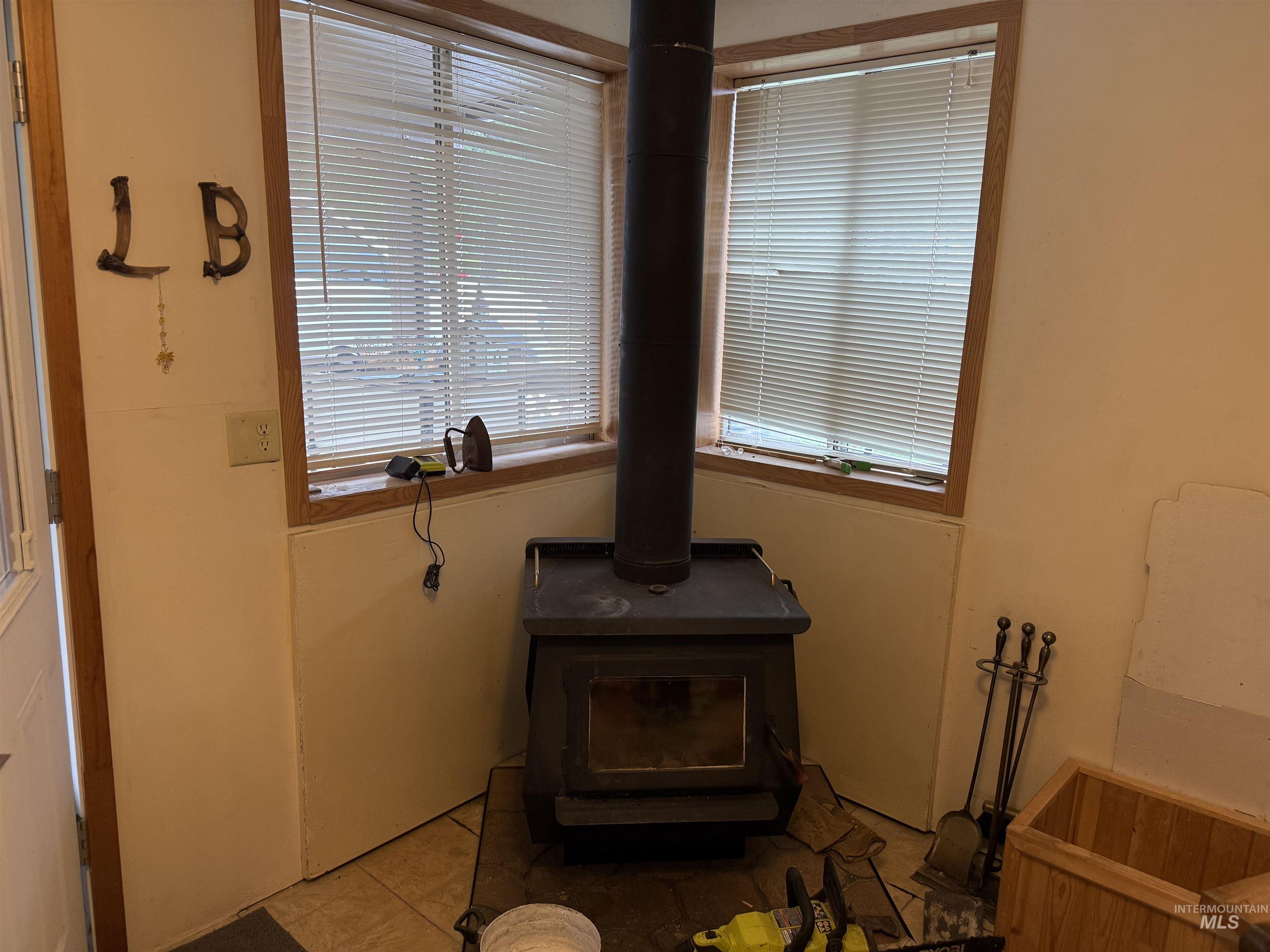733 Pleasant Valley Road Stites, ID 83552 - Photo 19 of 46 Corner wood-burning stove with a black finish, positioned on a tiled floor