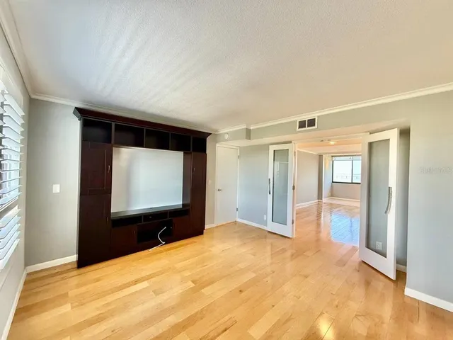 a view of an empty room with wooden floor and windows