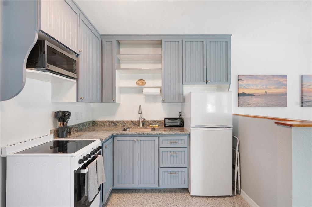 211 77th Street, Unit EAST Holmes Beach, FL 34217 - Photo 7 of 18 a kitchen with a sink a refrigerator and cabinets