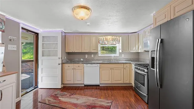 a kitchen with granite countertop stainless steel appliances a refrigerator cabinets and a sink