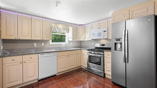 a kitchen with stainless steel appliances granite countertop a stove a refrigerator and a white cabinets