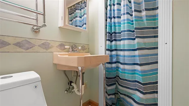 a bathroom with a sink a toilet and shower curtain