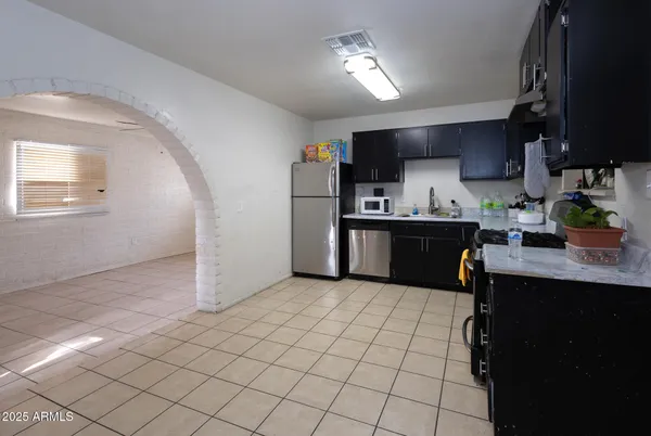 a kitchen with stainless steel appliances a sink a stove a refrigerator cabinets and a window