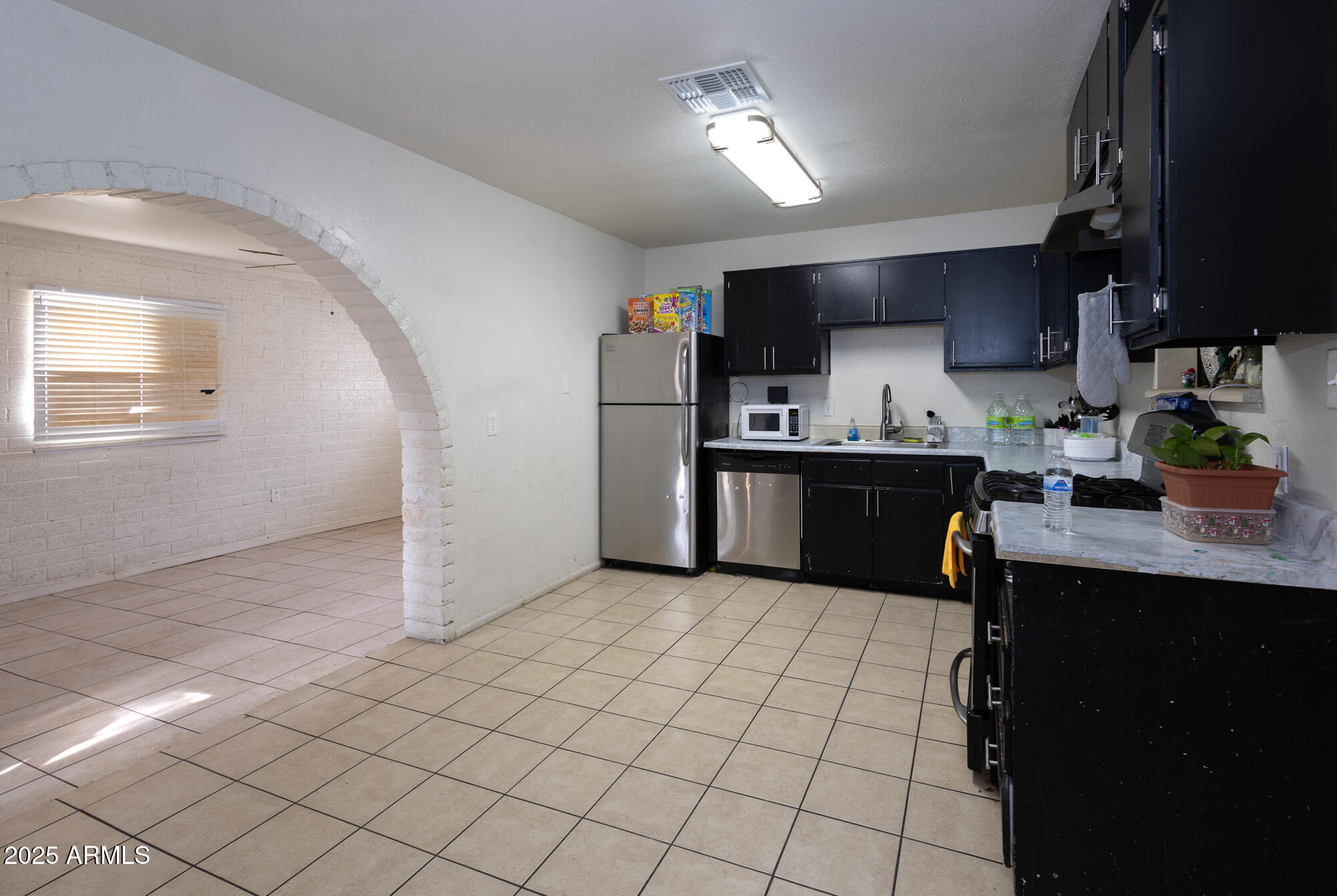 6826 South 8th Street Phoenix, AZ 85042 - Photo 4 of 22 a kitchen with stainless steel appliances a sink a stove a refrigerator cabinets and a window
