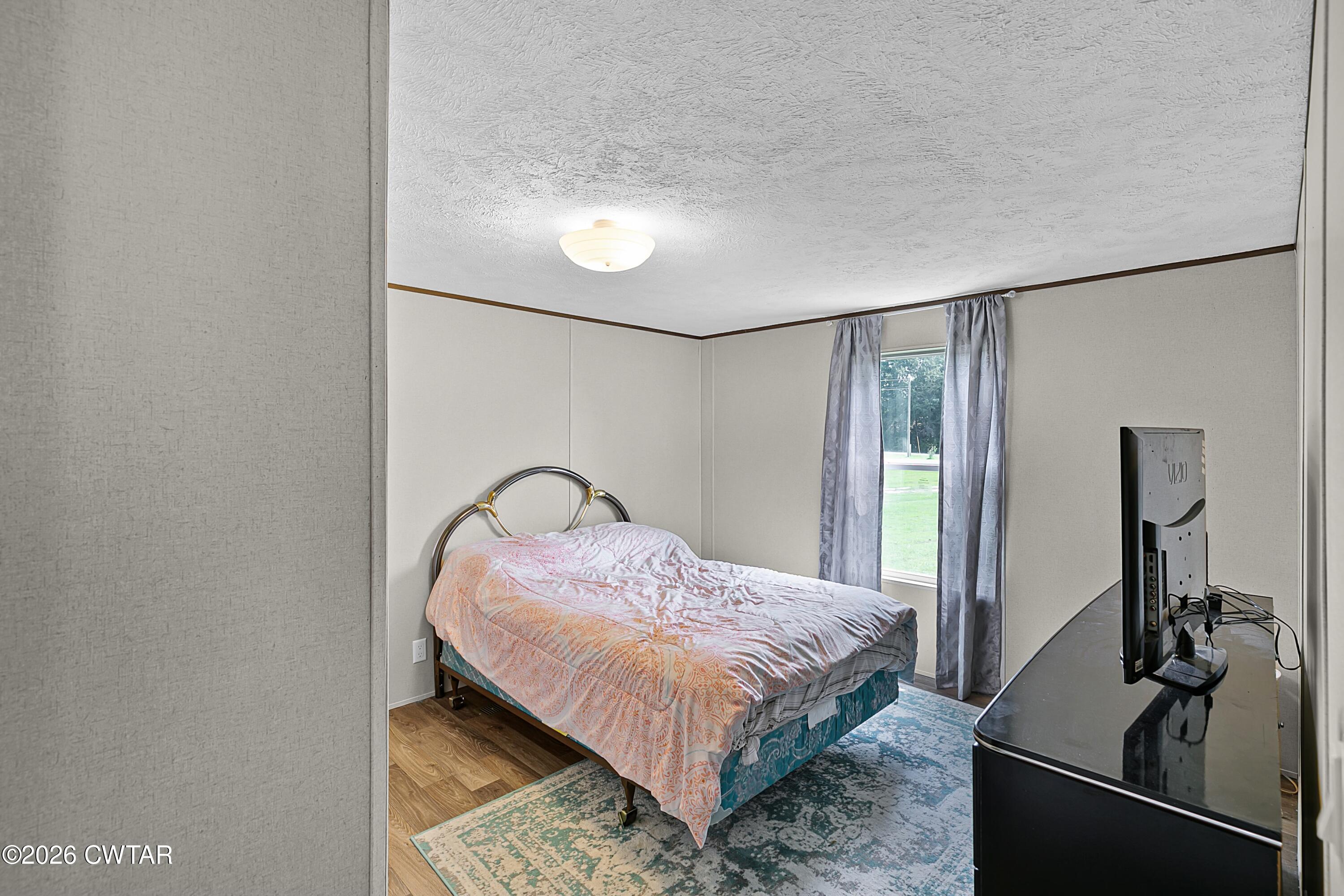 141 Persimmon Grove Road Trenton, TN 38382 - Photo 13 of 20 a bedroom with a bed and dresser with mirror