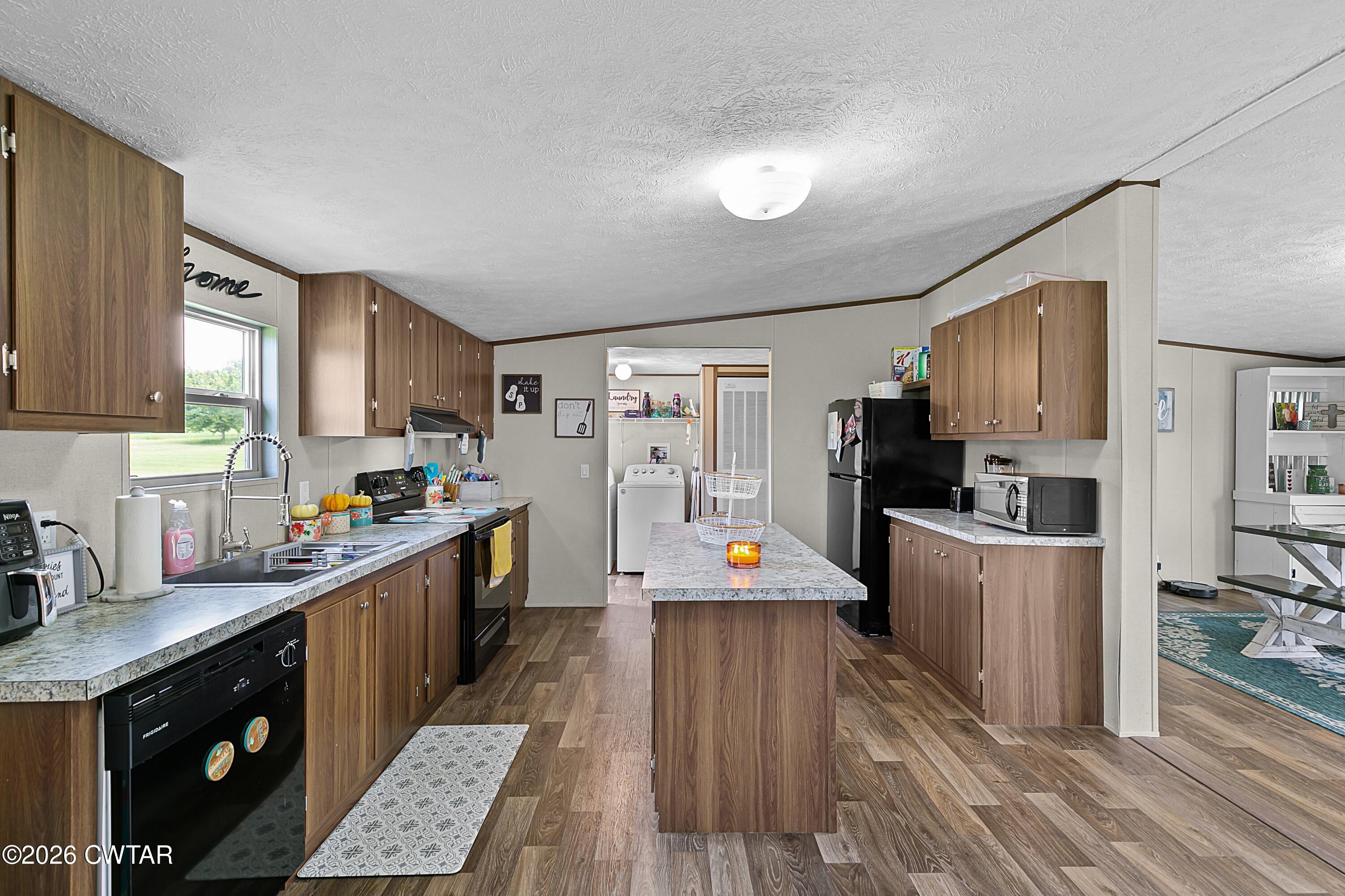 141 Persimmon Grove Road Trenton, TN 38382 - Photo 3 of 20 a large kitchen with stainless steel appliances wooden floors wooden cabinets a stove a sink and a refrigerator