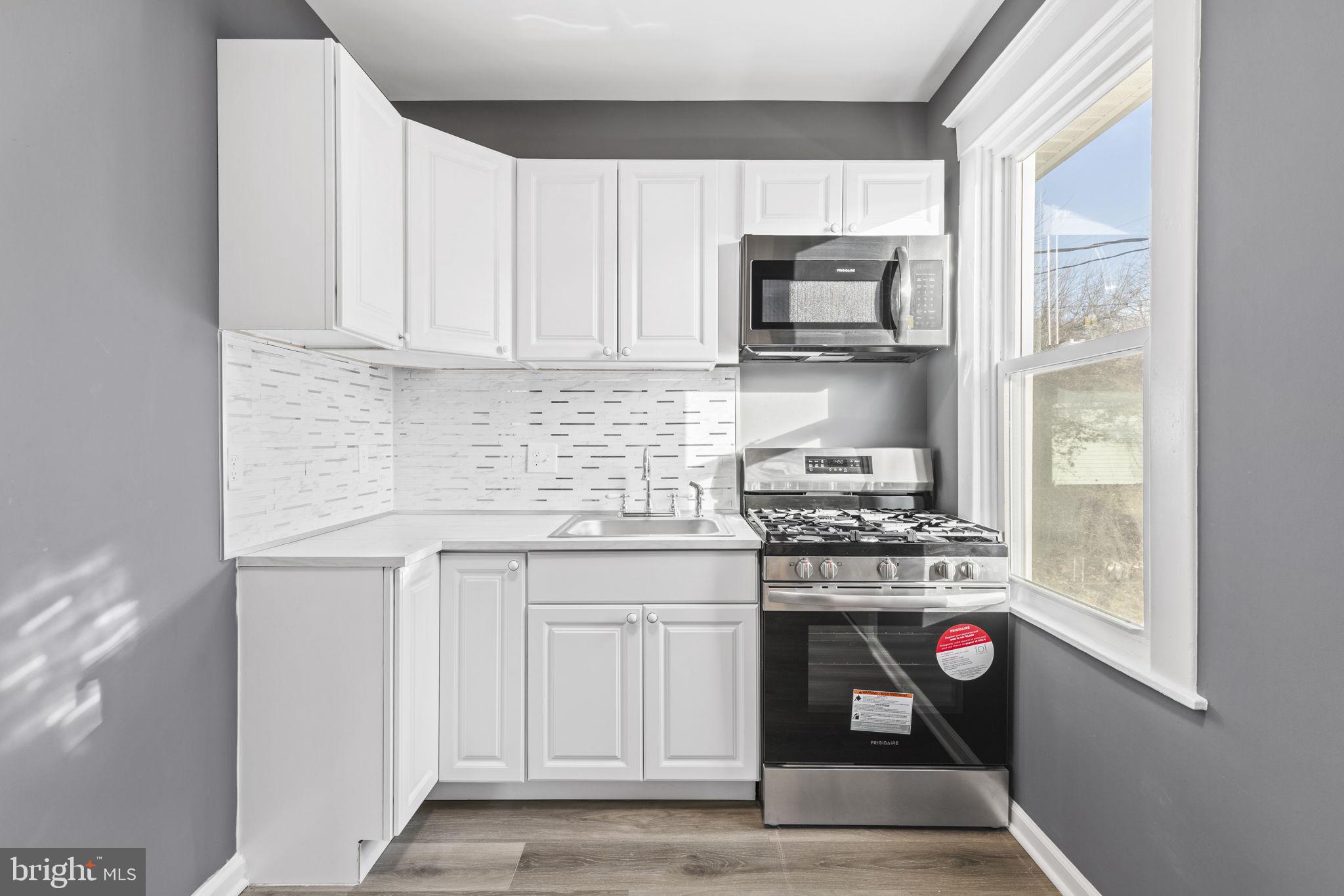 5613 Plymouth Road Baltimore, MD 21214 - Photo 6 of 31 a kitchen with stainless steel appliances granite countertop a stove and a microwave