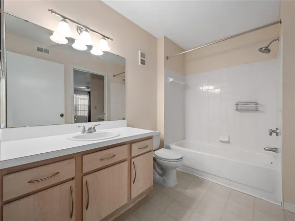 a bathroom with a toilet a sink a mirror a bathtub and vanity