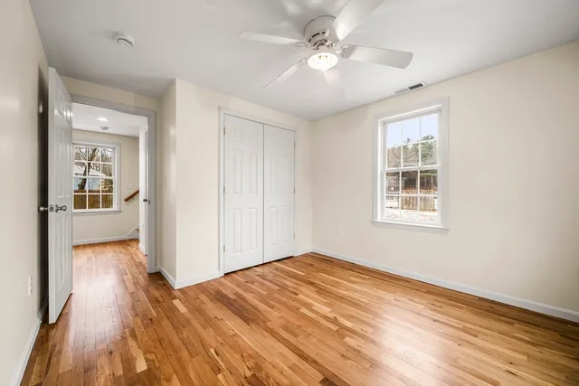 a view of an empty room with wooden floor and a window