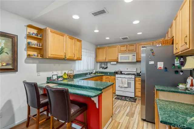 a kitchen with stainless steel appliances granite countertop a table chairs sink and cabinets