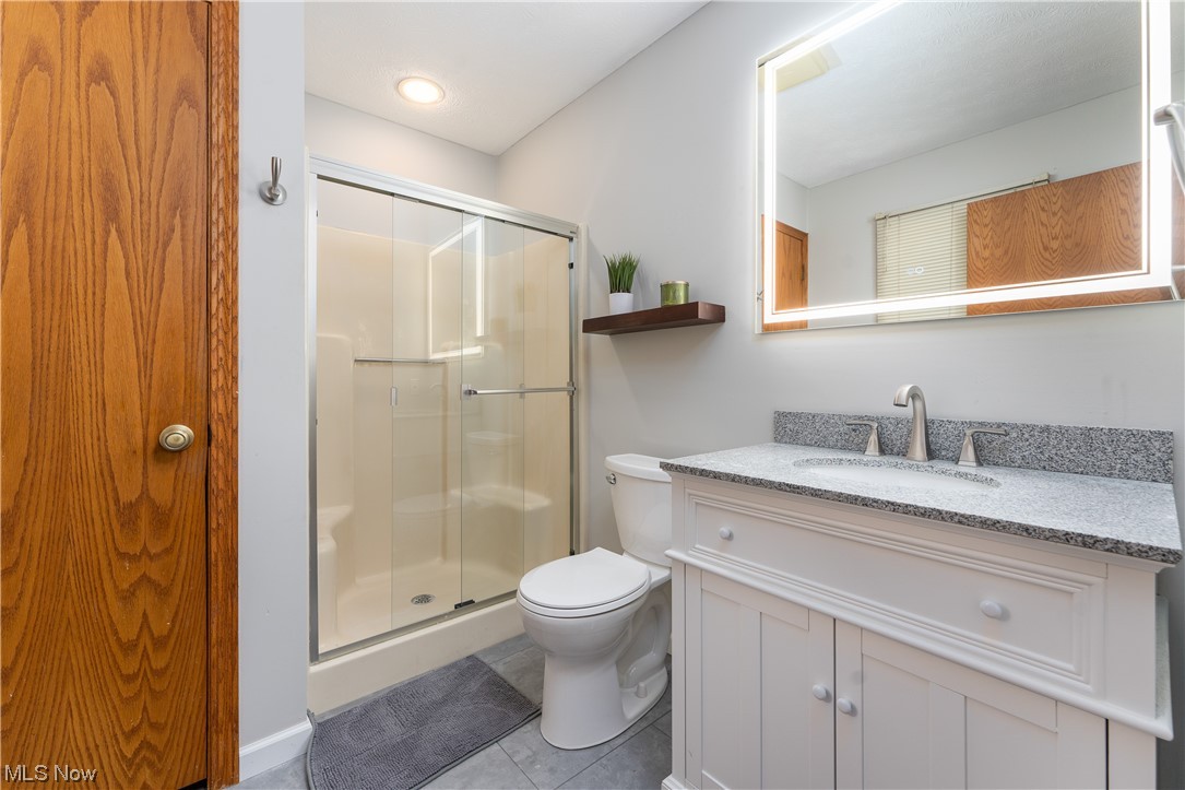 5226 Johnnycake Ridge Northeast Canton, OH 44705 - Photo 20 of 32 Bathroom featuring tile floors, vanity, a shower with shower door, and toilet