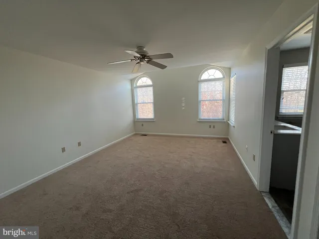 an empty room with windows and fan