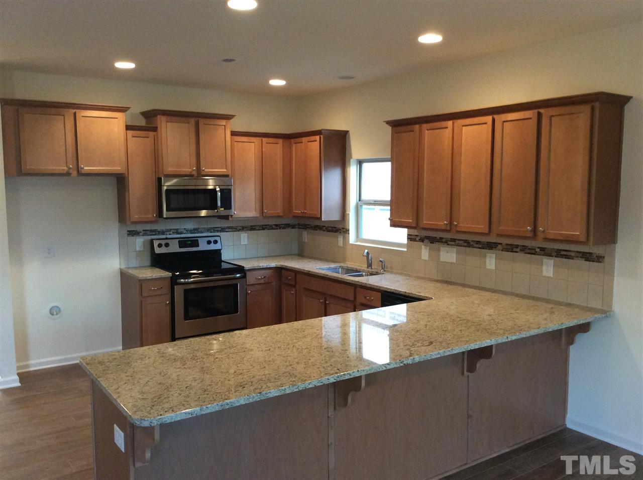 3633 Tule Spring Street Raleigh, NC 27610 - Photo 3 of 10 a kitchen with kitchen island granite countertop wooden cabinets a stove top oven a sink and dishwasher