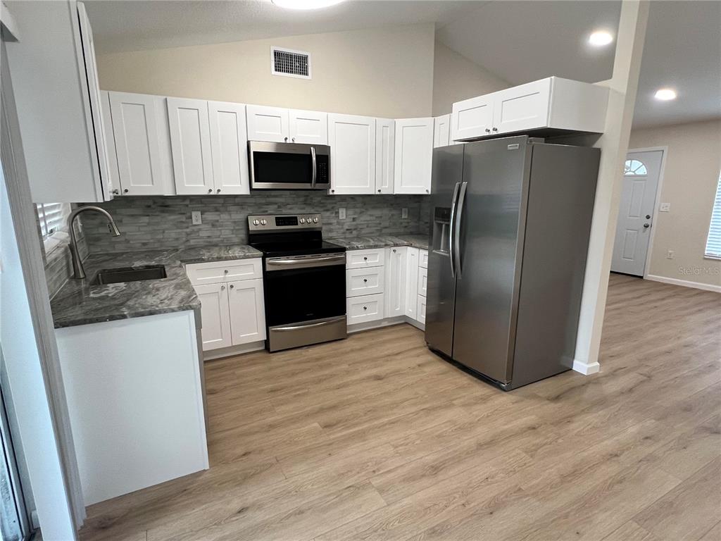 7224 Daggett Terrace New Port Richey, FL 34655 - Photo 2 of 14 a kitchen with stainless steel appliances granite countertop a refrigerator stove a sink and microwave