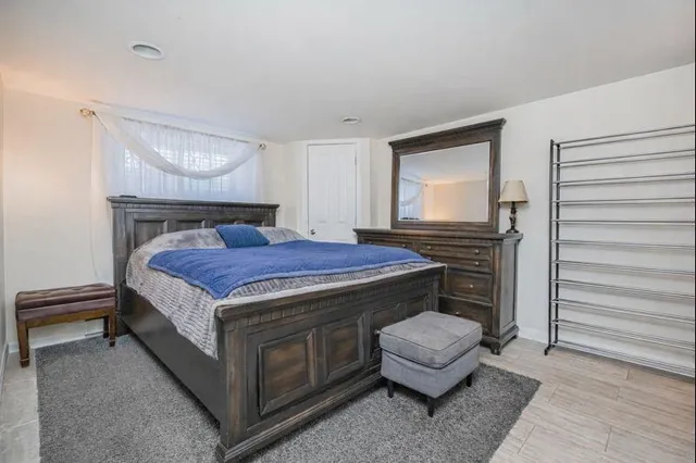 a bedroom with a bed and a dresser with wooden floor