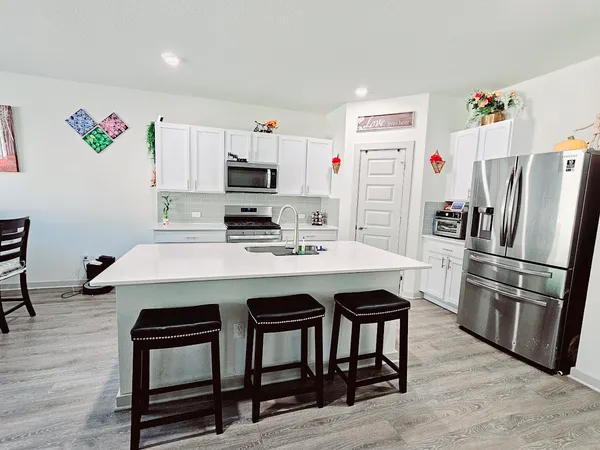 a kitchen with stainless steel appliances a table chairs and a refrigerator