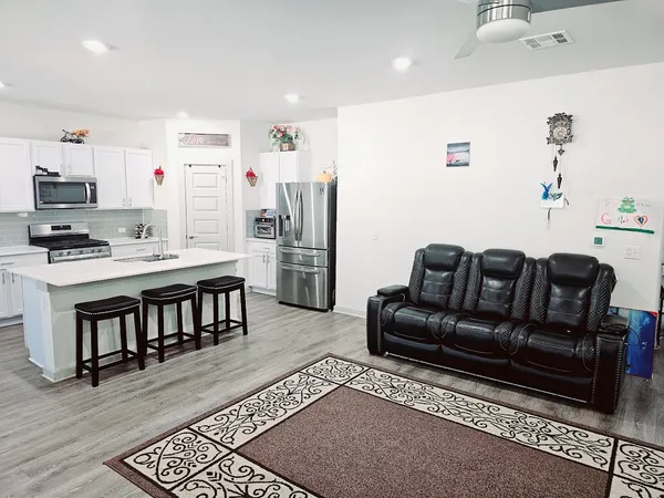 a living room with furniture a flat screen tv and a refrigerator