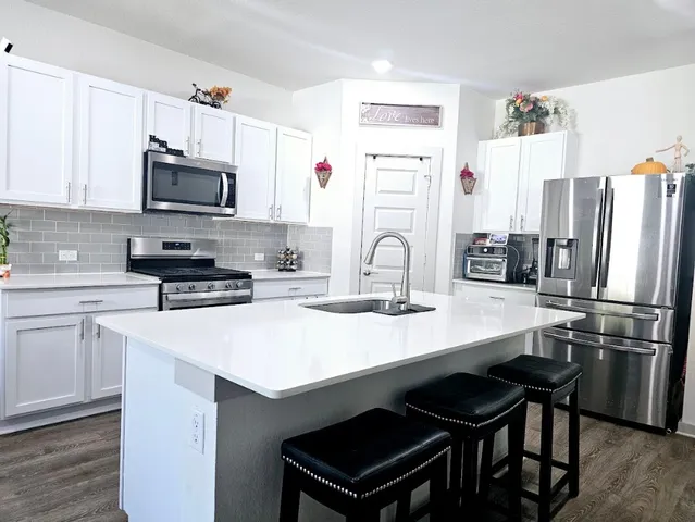 a kitchen with stainless steel appliances a sink a stove a refrigerator and cabinets