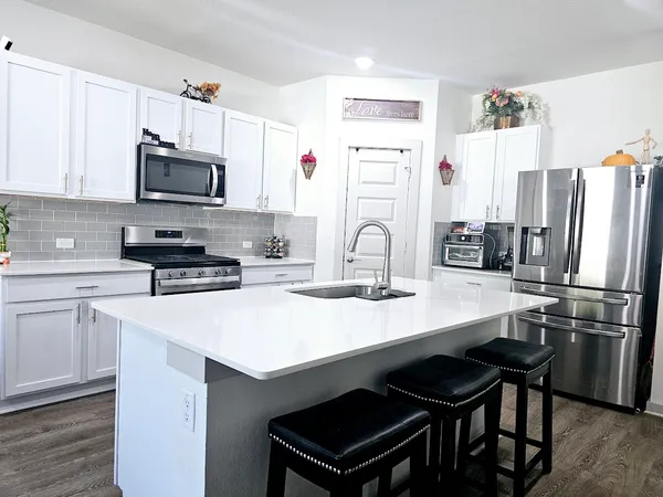 a kitchen with stainless steel appliances a sink a stove a refrigerator and cabinets