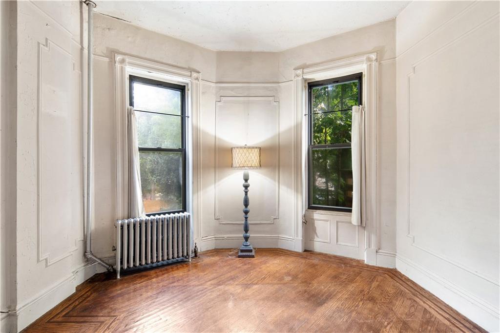 484 Decatur Street Brooklyn, NY 11233 - Photo 11 of 23 an empty room with wooden floor and windows