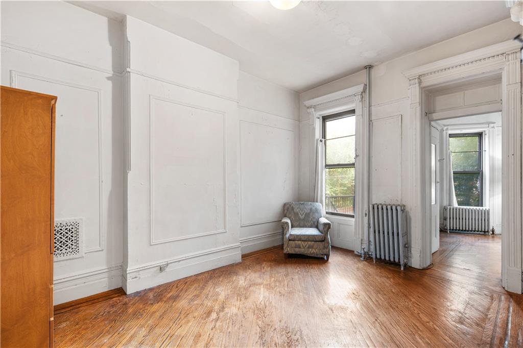 484 Decatur Street Brooklyn, NY 11233 - Photo 10 of 23 an empty room with wooden floor and windows