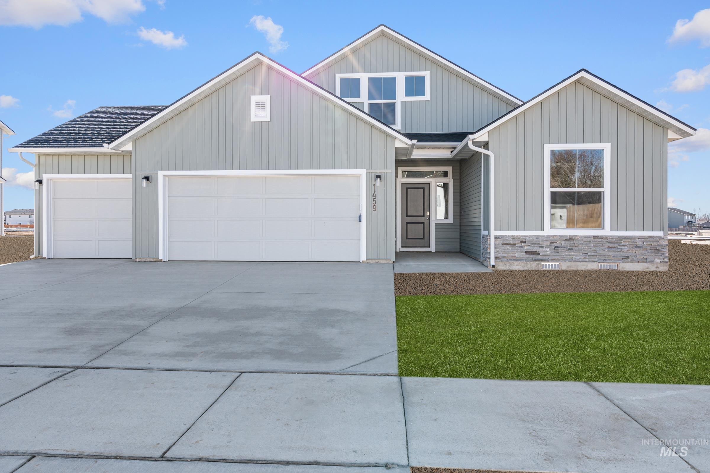 View of front of property with a garage, driveway, board and batten siding, a front yard, and a shingled roof