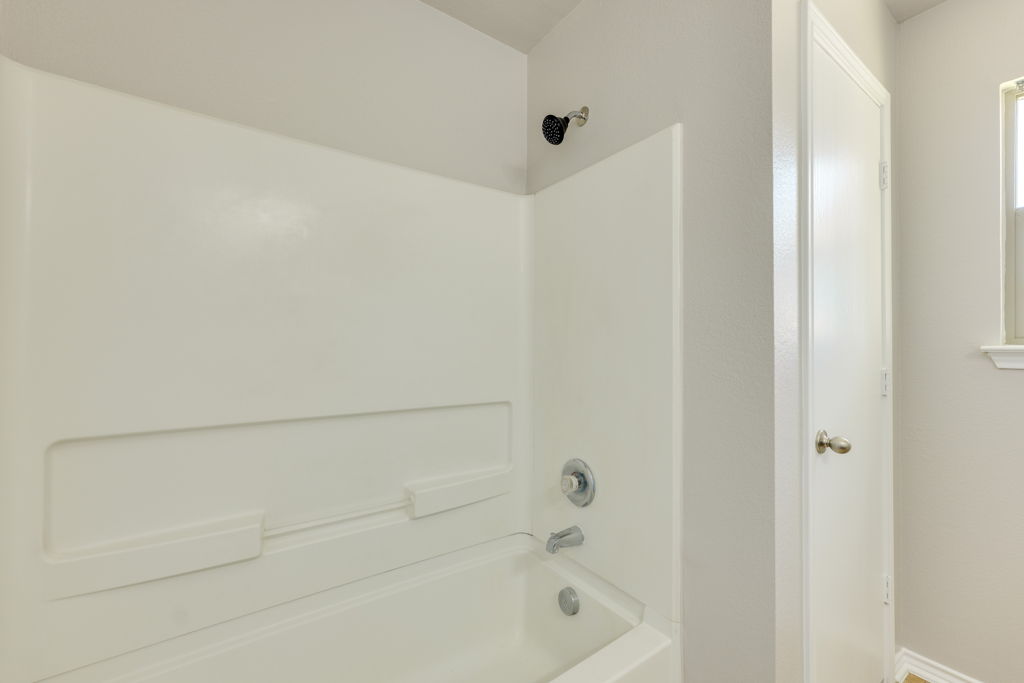 210 Cushman Drive Kyle, TX 78640 - Photo 16 of 21 Bathtub and shower combination featuring integrated shelving and a chrome faucet