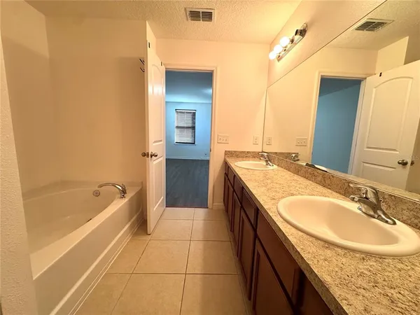 a bathroom with a granite countertop sink a bathtub and a mirror