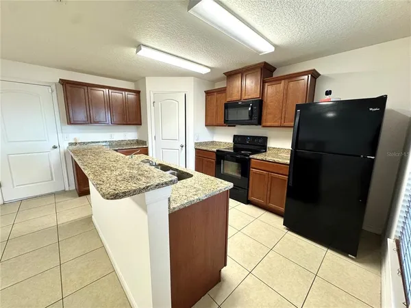 a kitchen with granite countertop a refrigerator and a stove top oven