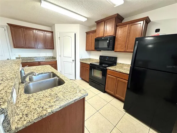 a kitchen with stainless steel appliances granite countertop a sink stove microwave and refrigerator
