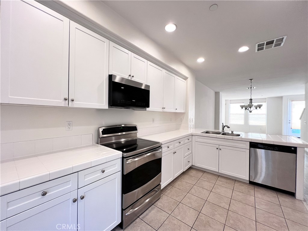 58 South 5th Street, Unit F Alhambra, CA 91801 - Photo 7 of 24 a kitchen with stainless steel appliances granite countertop a sink and dishwasher a stove top oven with white cabinets
