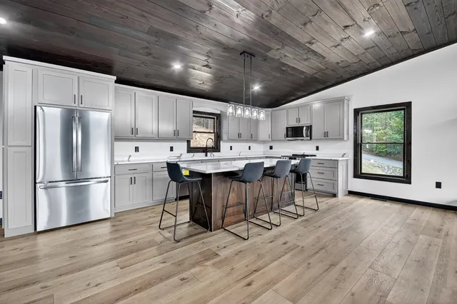 a kitchen with stainless steel appliances a refrigerator a stove a sink dishwasher a dining table and chairs with wooden floors