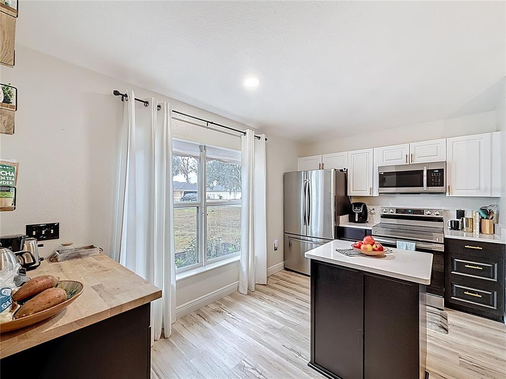 14908 Southwest 46th Circle Ocala, FL 34473 - Photo 6 of 46 a room with stainless steel appliances kitchen island granite countertop a refrigerator a sink dishwasher a stove and a dining table with wooden floor
