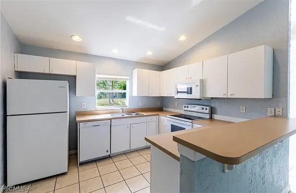 a kitchen with a sink a stove a refrigerator and white cabinets