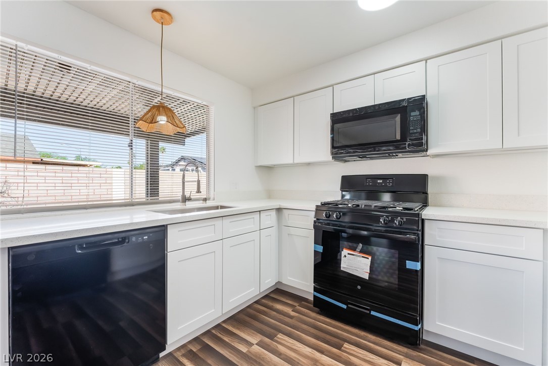 3597 Bronco Road Las Vegas, NV 89103 - Photo 21 of 43 Kitchen featuring black appliances, white cabinetry, dark wood-style floors, pendant lighting, and light stone countertops. Overlooking the pool and backyard.