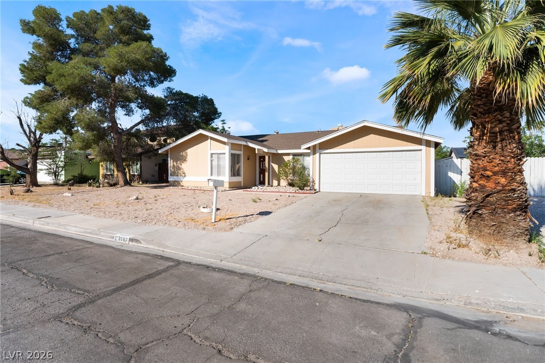 Ranch-style house with concrete driveway, an attached garage, and roof mounted solar panels