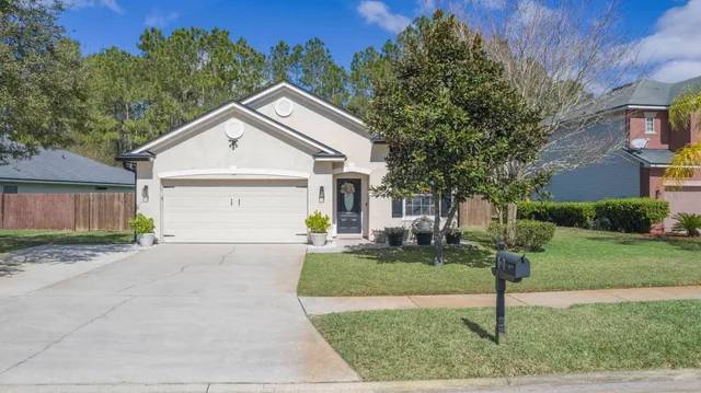 a view of a white house with a yard and large tree