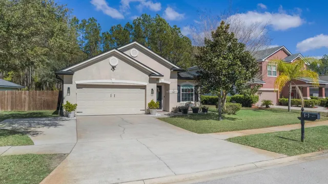 a view of a house with a yard and large tree