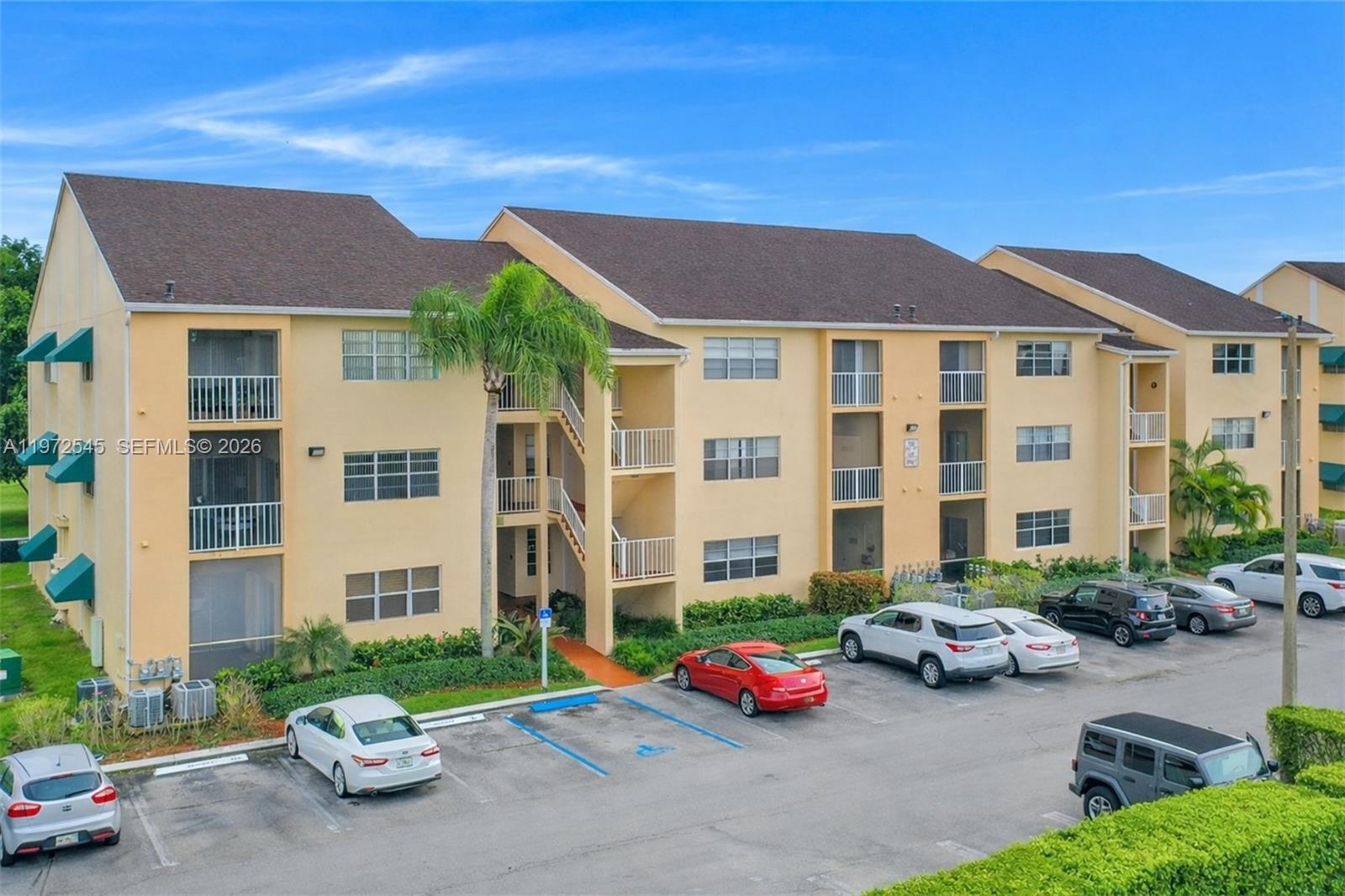 15285 Southwest 107th Lane, Unit 201 Miami, FL 33196 - Photo 1 of 28 a front view of a building with cars parked