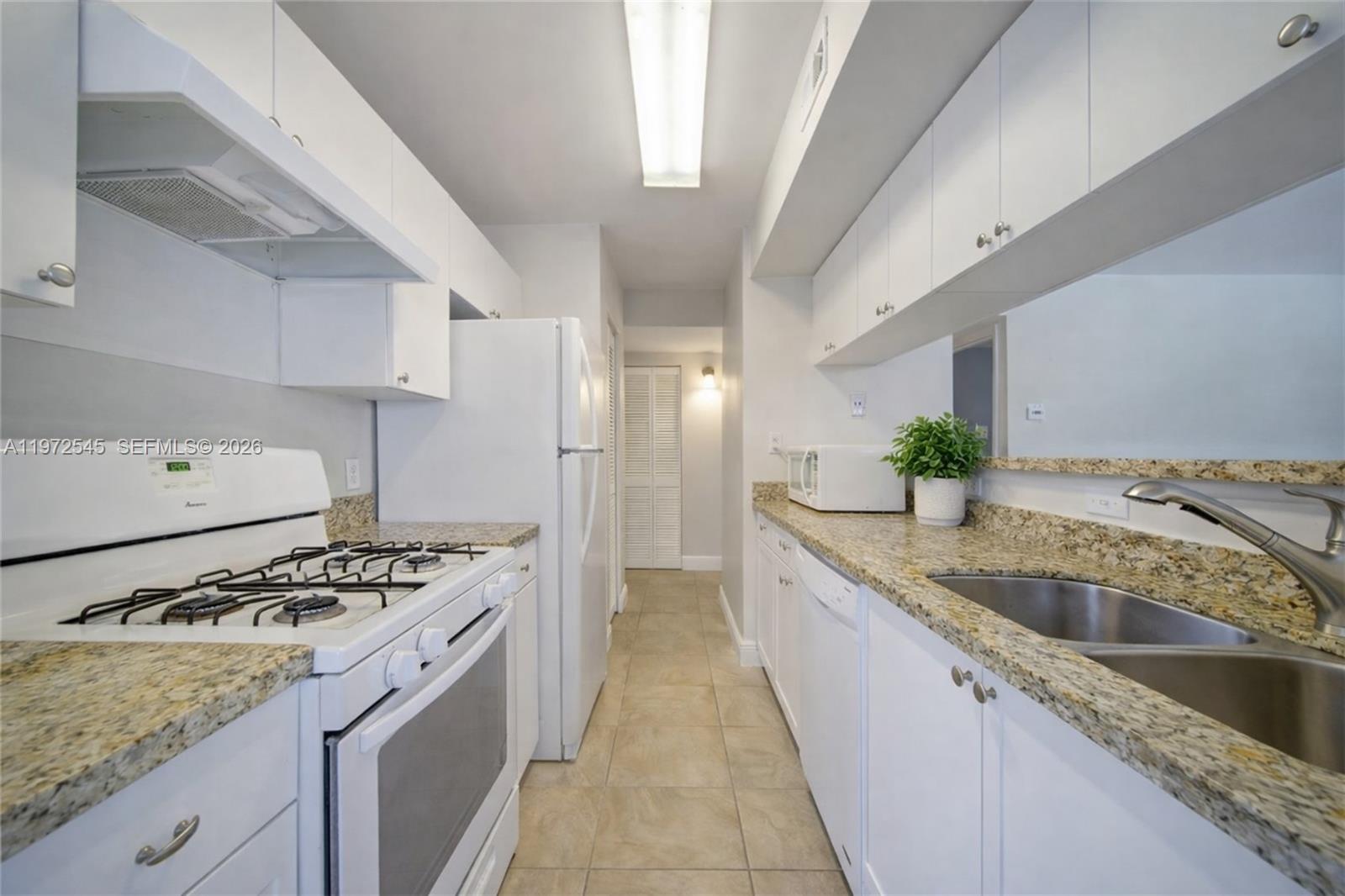 15285 Southwest 107th Lane, Unit 201 Miami, FL 33196 - Photo 14 of 28 a kitchen with granite countertop a sink stove and cabinets