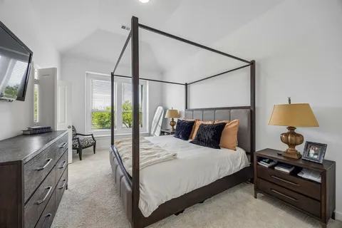 a bedroom with a bed and a flat tv screen on the dresser