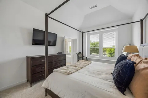 a bedroom with a bed and a flat tv screen on dresser