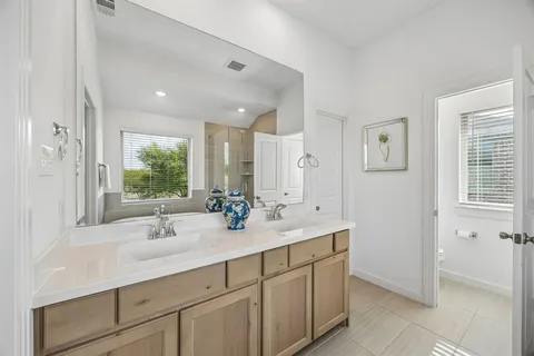 a bathroom with double vanity sinks a large mirror and a shower
